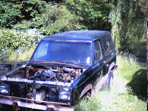 1987 Ford Bronco II - This 1987 Ford Bronco II is seen with its hood open, parked in a grassy, overgrown area.