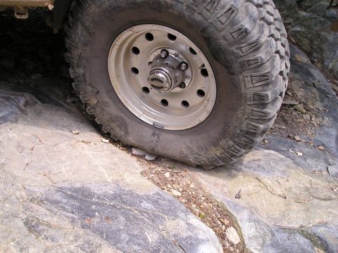 1996 Ford Bronco - A vehicle's tire navigates a challenging rocky terrain, highlighting its off-road capabilities.