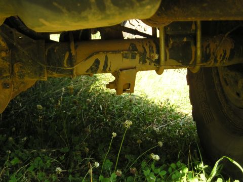 1996 Ford Bronco - Undercarriage view of a heavily soiled rear axle and suspension components, with a tire on the right.