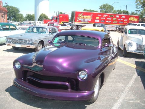 1994 Ford Bronco - A heavily modified purple coupe is parked at an outdoor car show with other vehicles present.