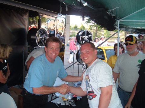 1994 Ford Bronco - Two men shake hands at an outdoor event with car wheels displayed.