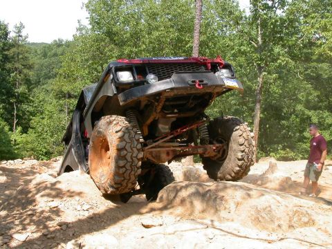 1990 Ford Bronco - A heavily modified off-road vehicle navigates a rocky incline, demonstrating its off-road capabilities.