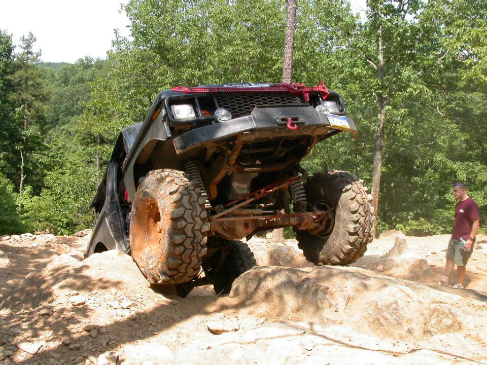 Modified off-road vehicle with large tires climbing rocks