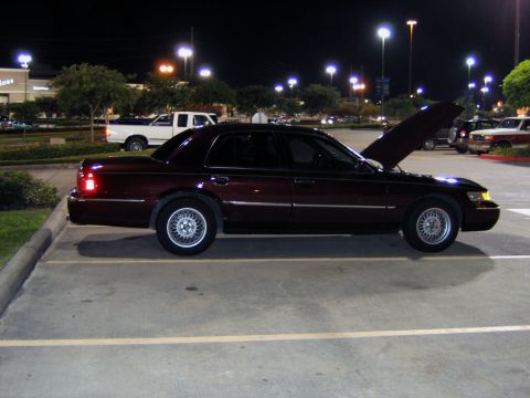 2000 Ford Crown Victoria - Maroon sedan parked in a lot at night with its hood up, other vehicles visible.