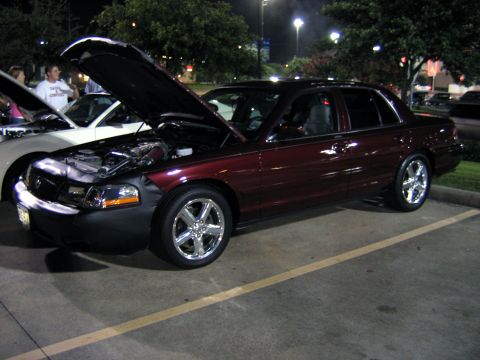 2000 Ford Crown Victoria - A dark red 2000 Ford Crown Victoria sedan is parked with its hood open, revealing the engine bay.