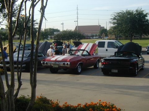 2000 Ford Crown Victoria - Several cars are parked at an outdoor event, with people milling around.