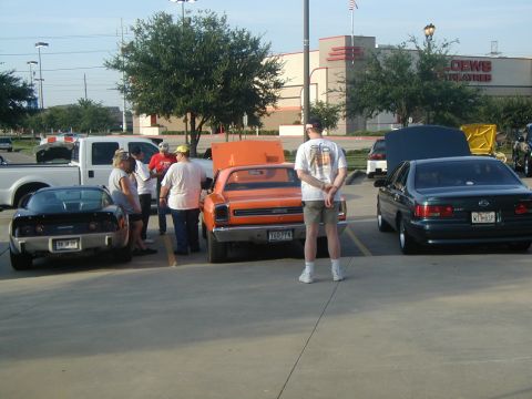 2000 Ford Crown Victoria - Several vehicles and people are gathered in a parking lot, with a movie theater in the background.
