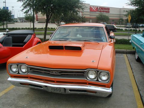 2000 Ford Crown Victoria - Front view of a 1969 Plymouth GTX parked next to another vehicle.