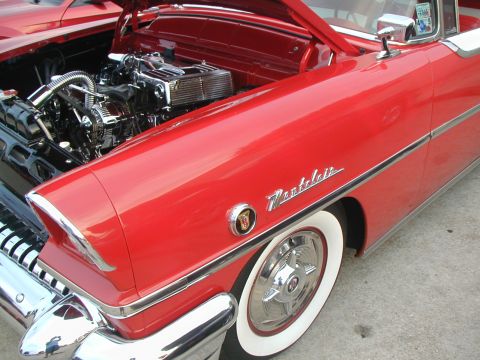 2000 Ford Crown Victoria - A red 1950s Mercury Montclair shows off its engine and classic styling with whitewall tires.