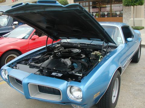 2000 Ford Crown Victoria - Blue 1973 Pontiac Firebird with hood open, parked next to a red car.