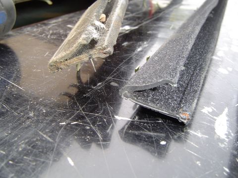 1989 Ford Bronco - Two pieces of old rubber window seal are shown on a dirty, scratched surface.