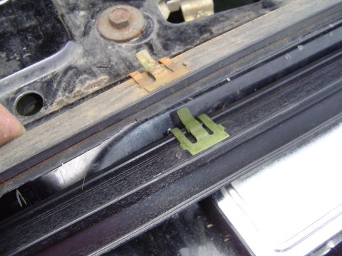 1989 Ford Bronco - Green and rusty clips are attached to a black rubber window seal, likely for a vehicle.