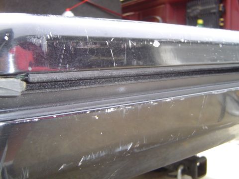 1989 Ford Bronco - Close-up of a worn tailgate window seal on a dark-colored vehicle, showing significant surface damage.