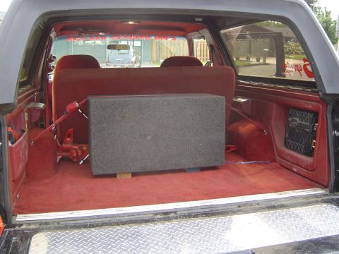 1989 Ford Bronco - The rear cargo area of a 1989 Ford Bronco shows a large subwoofer and an amplifier installed.