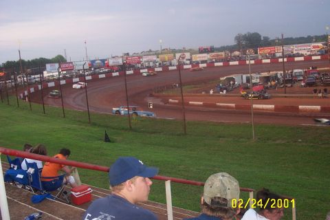 1979 Ford F-150 - A dirt racetrack hosts a race with multiple cars on the track and spectators in the stands, captured on February 24, 2001.