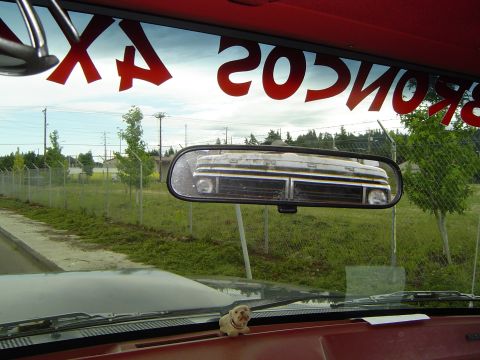 1972 Ford F-100 - Reflection of a 1970s truck grille in the rearview mirror, with red lettering on the windshield.