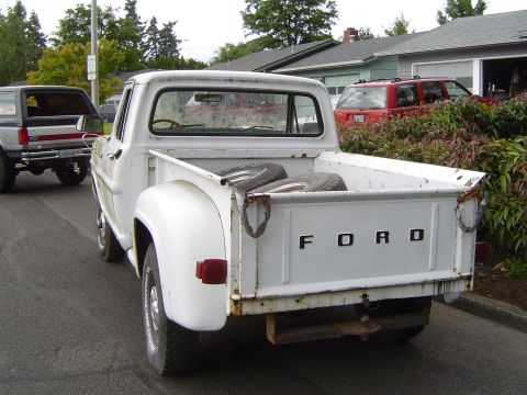 1972 Ford F-100 - This white 1972 Ford F-100 pickup truck is seen from the rear, with spare tires loaded in its bed.
