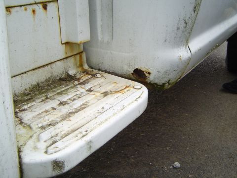 1972 Ford F-100 - The rear step and fender of a white truck show significant rust and grime, indicating wear and tear.