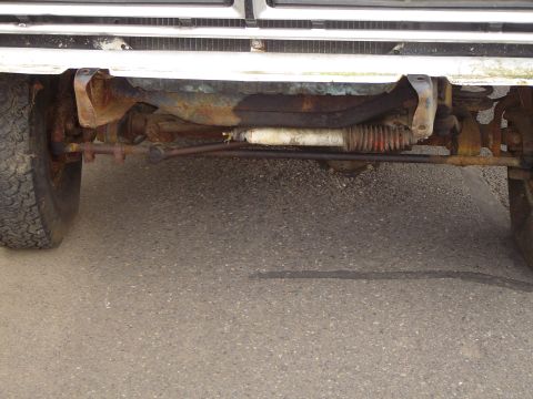 1972 Ford F-100 - Close-up view of a white truck's front axle and steering components, showing signs of rust.
