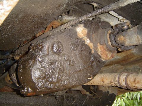 1972 Ford F-100 - Underside view of a greasy transfer case and driveshaft, likely from an older truck.