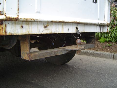 1972 Ford F-100 - The rear of a white truck shows significant rust on the bumper and a trailer hitch assembly.