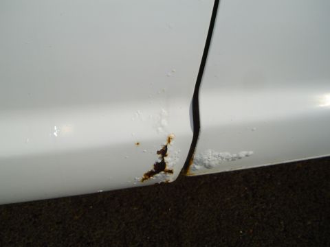 1972 Ford F-100 - Rust damage is visible on the lower portion of a white truck's door seam.