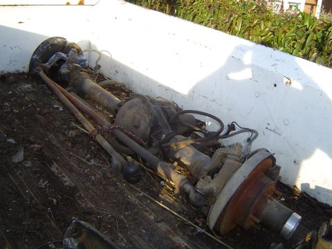 1972 Ford F-100 - A disassembled truck rear axle assembly lies in the bed of a pickup truck, showing the differential and brake components.