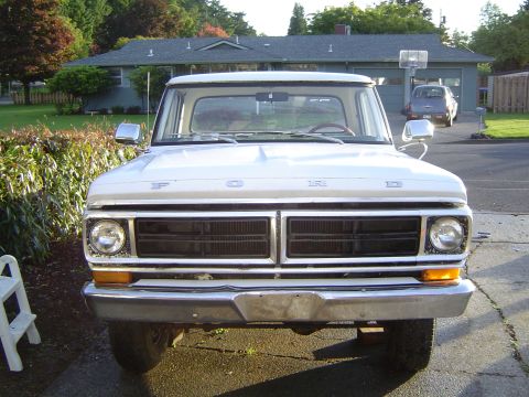 1972 Ford F-100 - Front view of a white Ford F-100 truck parked in a driveway with a house and another vehicle in the background.