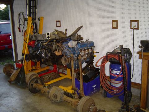 1972 Ford F-100 - Engine and chassis components are displayed on stands in a garage setting.