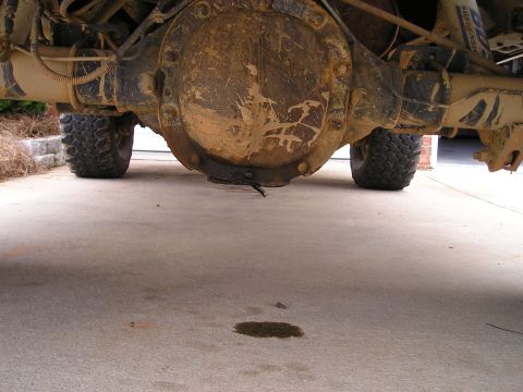 1996 Ford Bronco - A low-angle shot captures the rear of a brown SUV, focusing on its tires and the ground beneath.