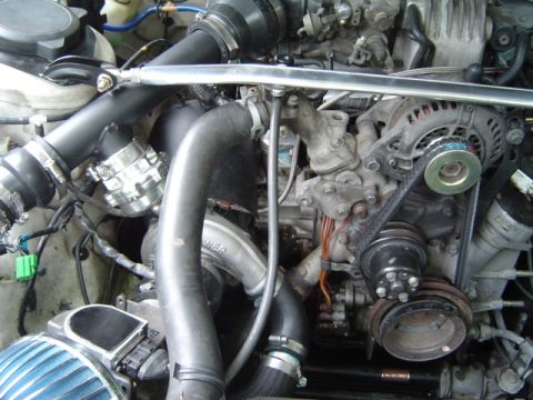 1986 Mazda RX-7 - Close-up view of a modified engine bay, highlighting the turbocharger and associated plumbing.