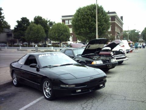 1995 Ford Probe - A line of cars are parked in a lot, with several having their hoods open.