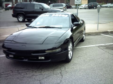 1995 Ford Probe - A black 1995 Ford Probe is parked in a lot, with other vehicles visible in the background.
