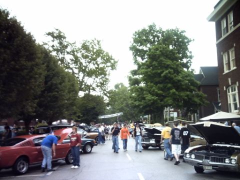 1995 Ford Probe - A street lined with classic cars and people attending an outdoor event.