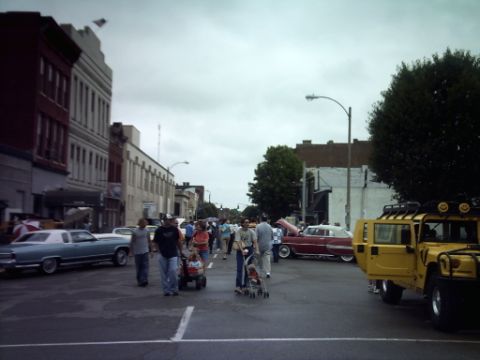 1995 Ford Probe - A street scene with a yellow Hummer H1 and a blue sedan, along with pedestrians and other vehicles.