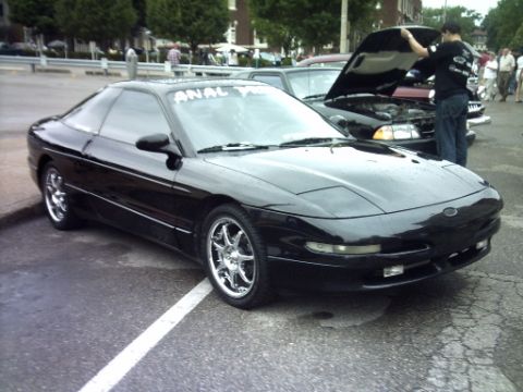 1995 Ford Probe - A black coupe is parked on asphalt, with another vehicle's hood open in the background.