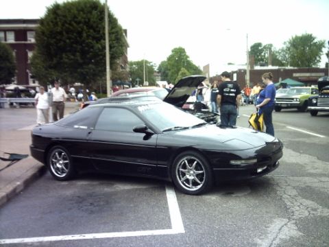 1995 Ford Probe - A black 1995 Ford Probe is displayed at an outdoor event with other vehicles and people.