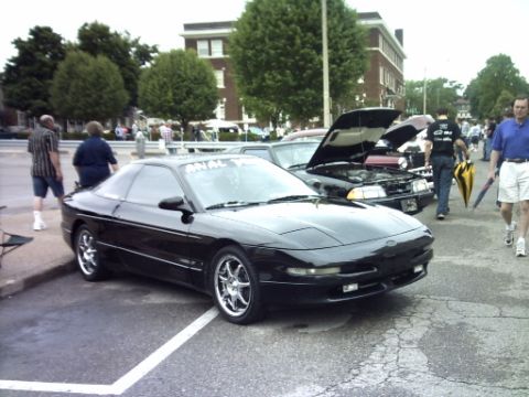 1995 Ford Probe - A black 1995 Ford Probe is parked at an outdoor event with other vehicles present.