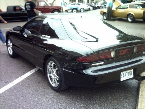 1995 Ford Probe - A black Ford Probe GT is parked on the street, with other vehicles and people in the background.