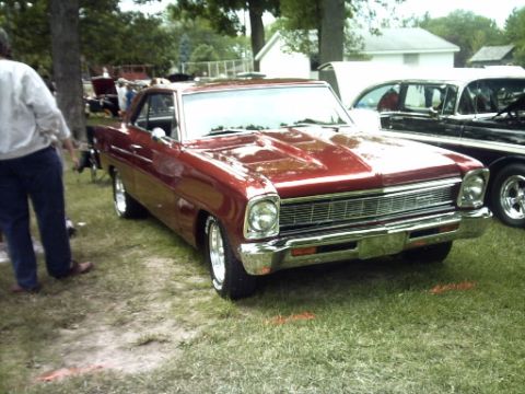 1995 Ford Probe - A classic red 1966 Chevrolet Nova is displayed outdoors next to another vehicle.