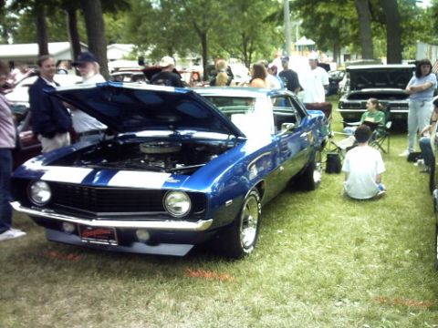 1995 Ford Probe - A blue classic car with white stripes is displayed with its hood open at an outdoor car show.