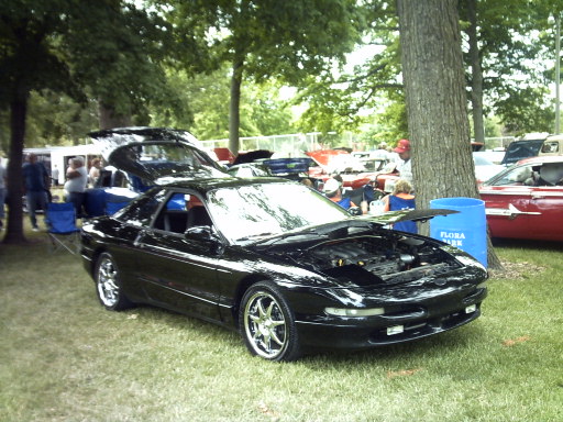 Black 1995 Ford Probe with hood open, parked on grass