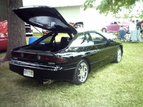 1995 Ford Probe - This black 1995 Ford Probe is displayed outdoors with its trunk open, surrounded by other vehicles and attendees.