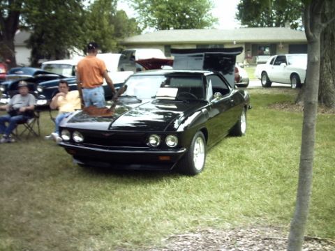 1995 Ford Probe - A black coupe is displayed with its hood open, parked on a grassy lawn with other vehicles and people around.