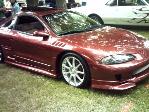 1995 Ford Probe - A red coupe with an aggressive body kit and aftermarket wheels is parked on grass, with another vehicle visible in the background.
