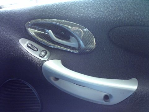 1995 Ford Probe - Close-up of a car's interior door panel carbon fiber trim around the door handle and window controls.