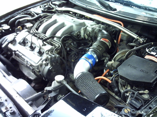 V6 engine bay with aftermarket cone intake, blue silicone coupler and orange plug wires