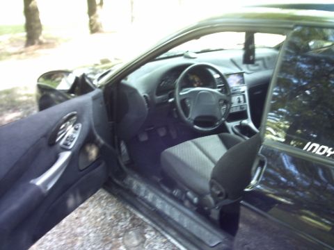 1995 Ford Probe - The interior of a black car is visible with the driver's door open, showing the dashboard and seats.