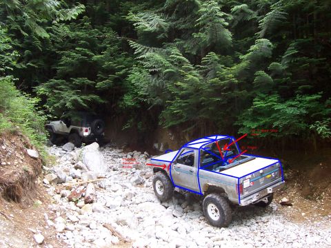 1984 Ford Bronco II - Two off-road vehicles navigate a rocky, wooded trail.