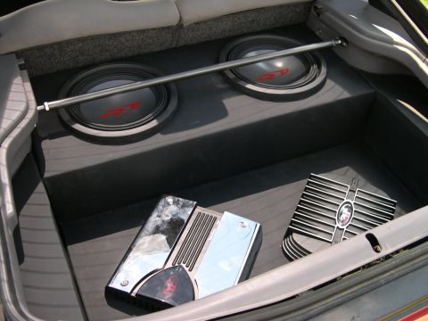 1997 Ford Probe - Hatch-area audio install with two Alpine Type-R subwoofers mounted in a black carpeted box, braced by a chrome strut bar running across the…